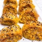 Cheesy sausage puff pastry bites feature image close up out of oven sliced.