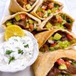 Easy Greek gyro pita pocket with tzatziki sauce feature image close up on platter with dipping sauce.