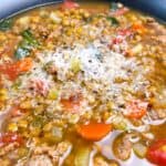 Hearty Italian Lentil Soup with Sausage and Spinach feature image close up in black bowl with parmesan topping.
