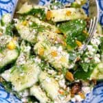 Mediterranean smashed cucumber salad feature image close up in blue bowl.