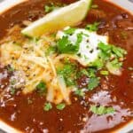 Tex Mex chili feature image close up in bowl with cilantro, cheese, and lime.