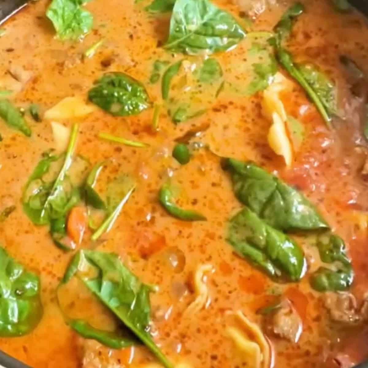 Creamy Tuscan Tortellini Soup process shot 4 fully cooked in pot with spinach.
