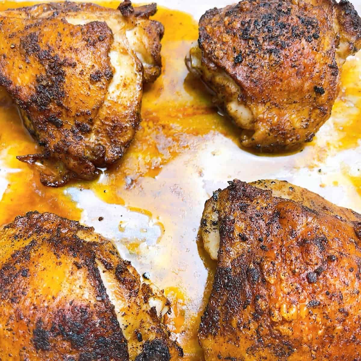 Chicken thighs cooked and resting in juices.