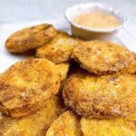 A feature image of fried green tomatoes on a platter with a serving of remoulade sauce.