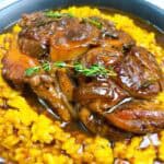 Classic osso buco with saffron risotto feature image close up of veal on risotto with gravy and herbs.