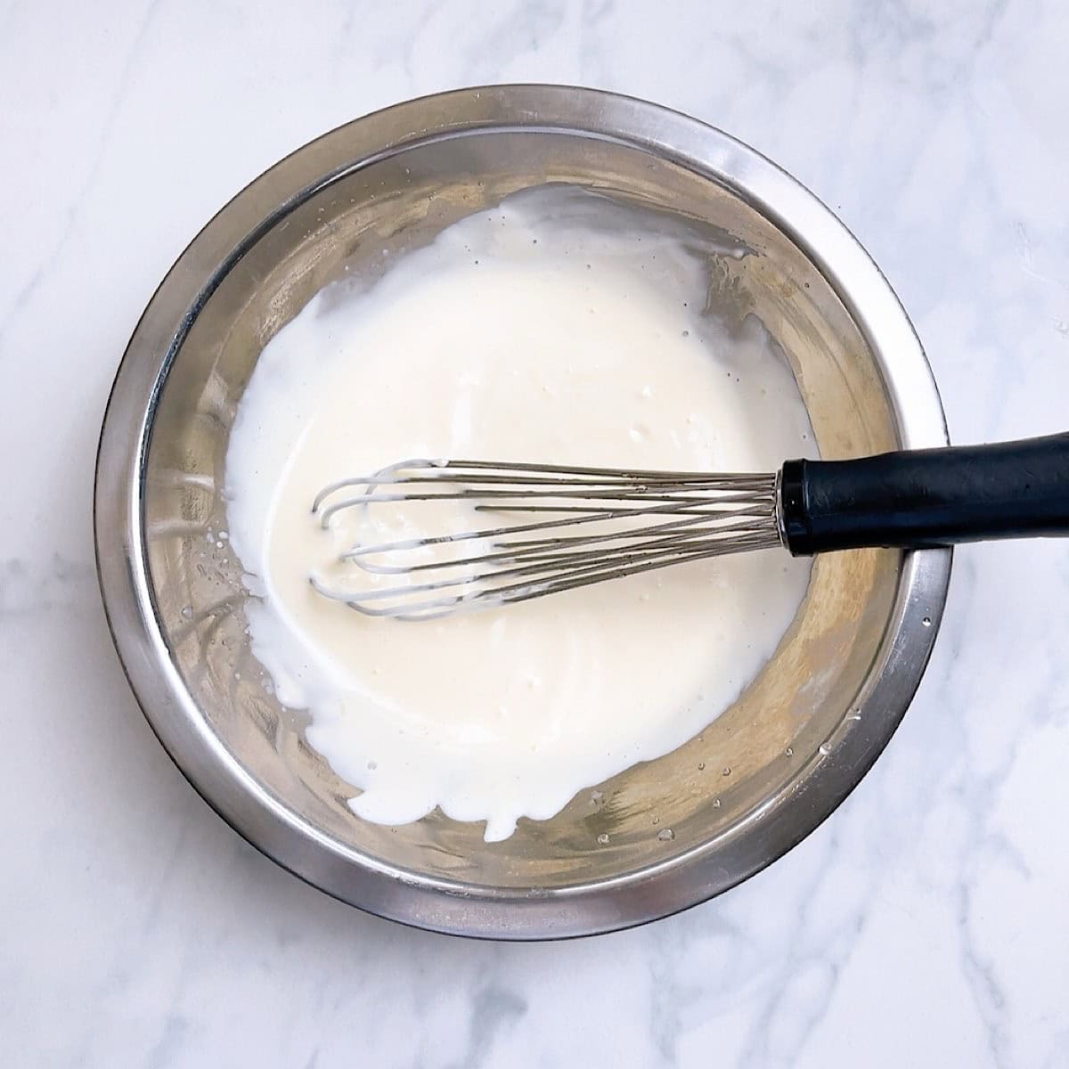 Mayonnaise, garlic, and lemon being whisked for garlic aioli dipping sauce.