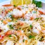 Shrimp scampi without wine in a white bowl with parsley, parmesan, and lemon.