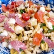 Zesty Italian pasta salad with garnish tossed in decorative blue bowl.