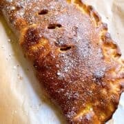 Calzone on brown parchment golden and toasty with parmesan.