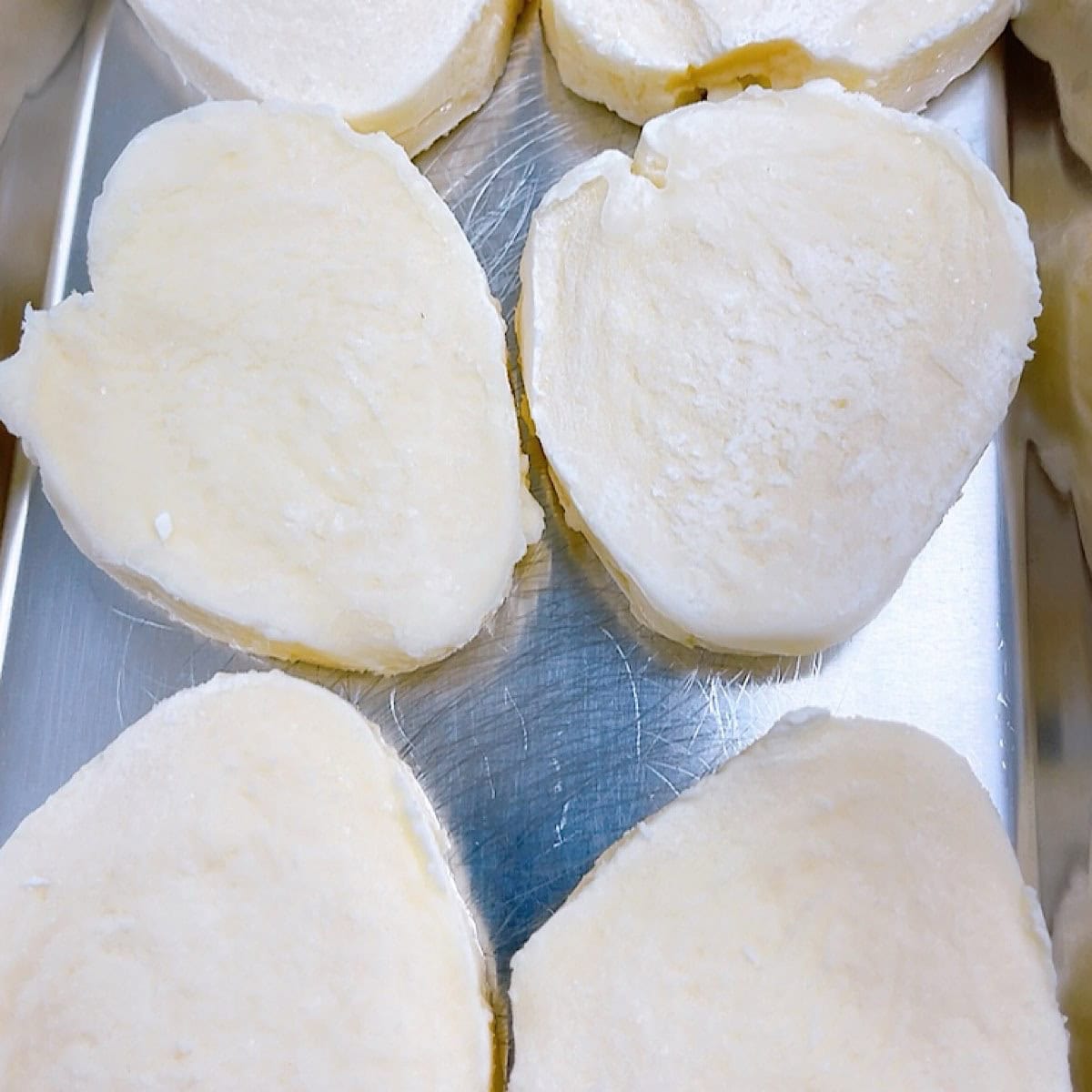 Frozen mozzarella rounds on a baking sheet.