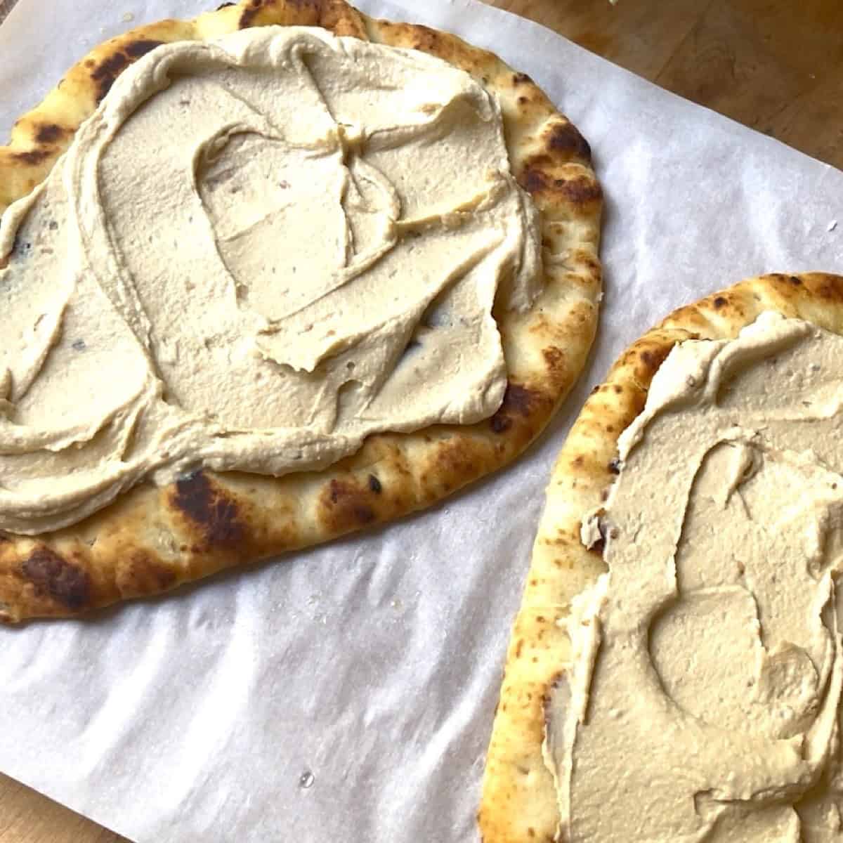 Hummus spread on two warmed pieces of Naan.