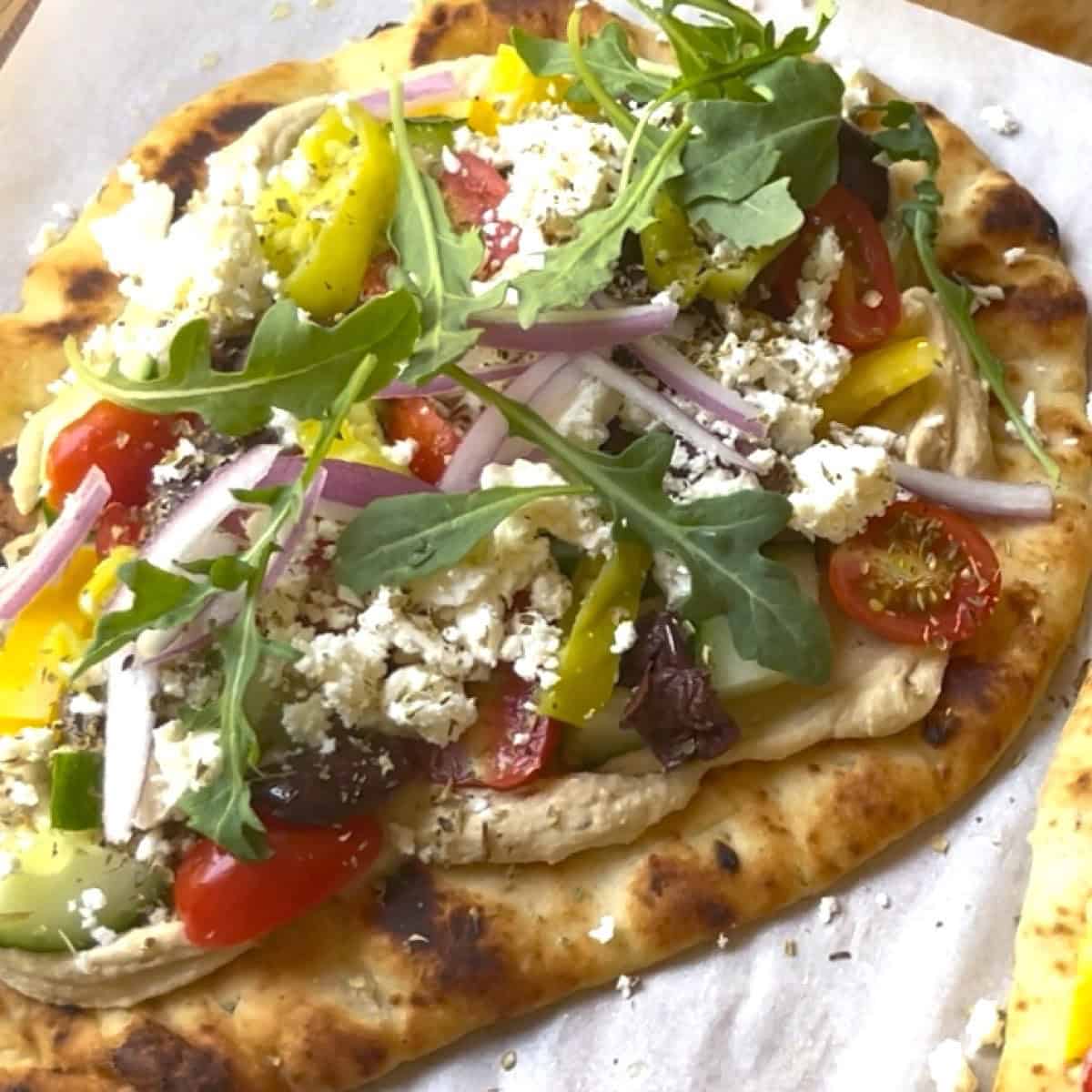 Adding arugula to the top of the Mediterranean flatbread pizza.