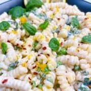 Creamy pasta with ricotta and peas in a black bowl.