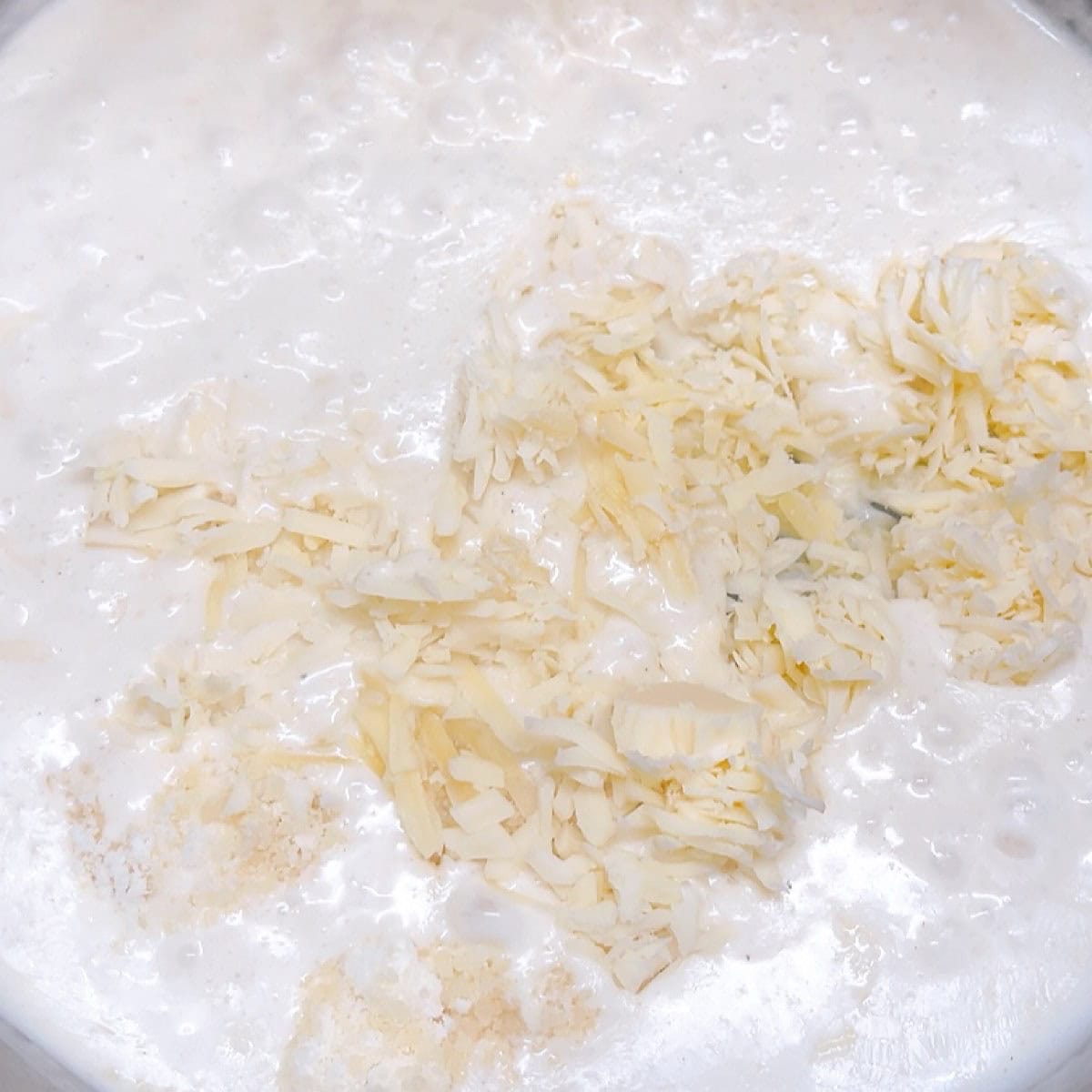 Adding cream and melting the cheese for bechamel.