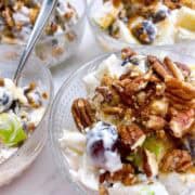 Apple grape salad in elegant glass dessert bowls with toppings.