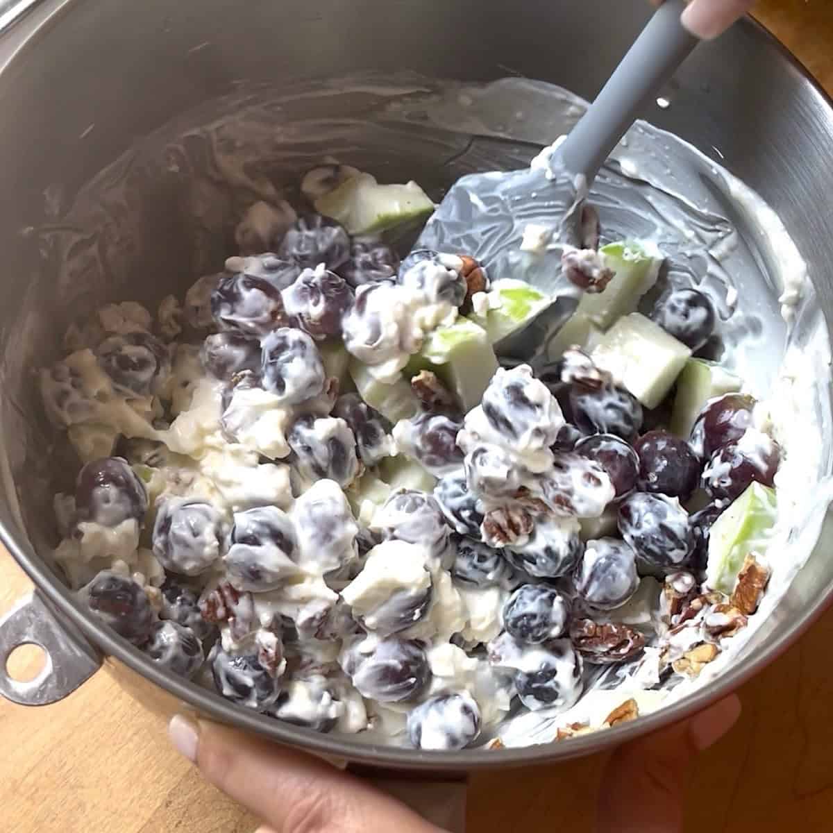 Grapes, apples, and pecans being folded into creamy base.