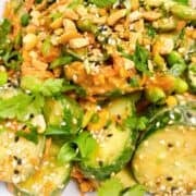 Crunchy cucumber salad with garnish in a white bowl.