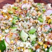 Quinoa cucumber salad with chickpeas, feta, and herbs in a decorative wooden bowl.