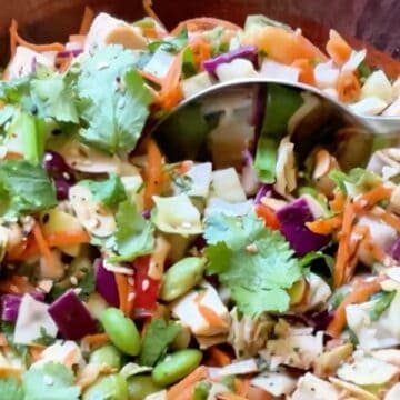 Asian bean salad in a large wooden bowl being dipped with a serving spoon.