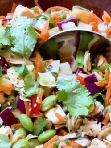 Asian bean salad in a large wooden bowl being dipped with a serving spoon.