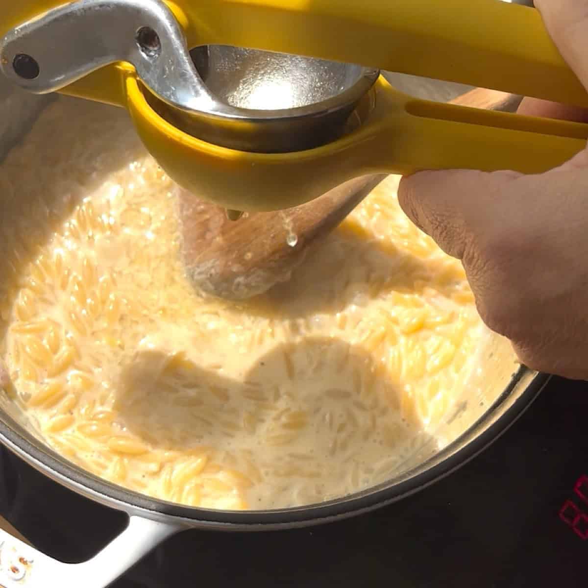 Adding fresh lemon to the creamy broth with a lemon squeezer.
