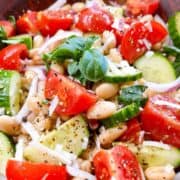 An Italian white bean salad in a wooden salad bowl with garnish.