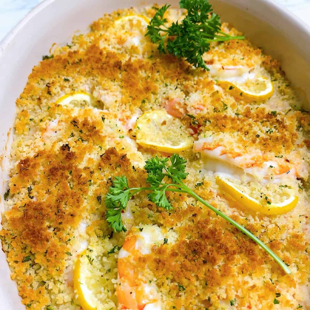 Baked shrimp scampi in a casserole dish with curly parsley on top.