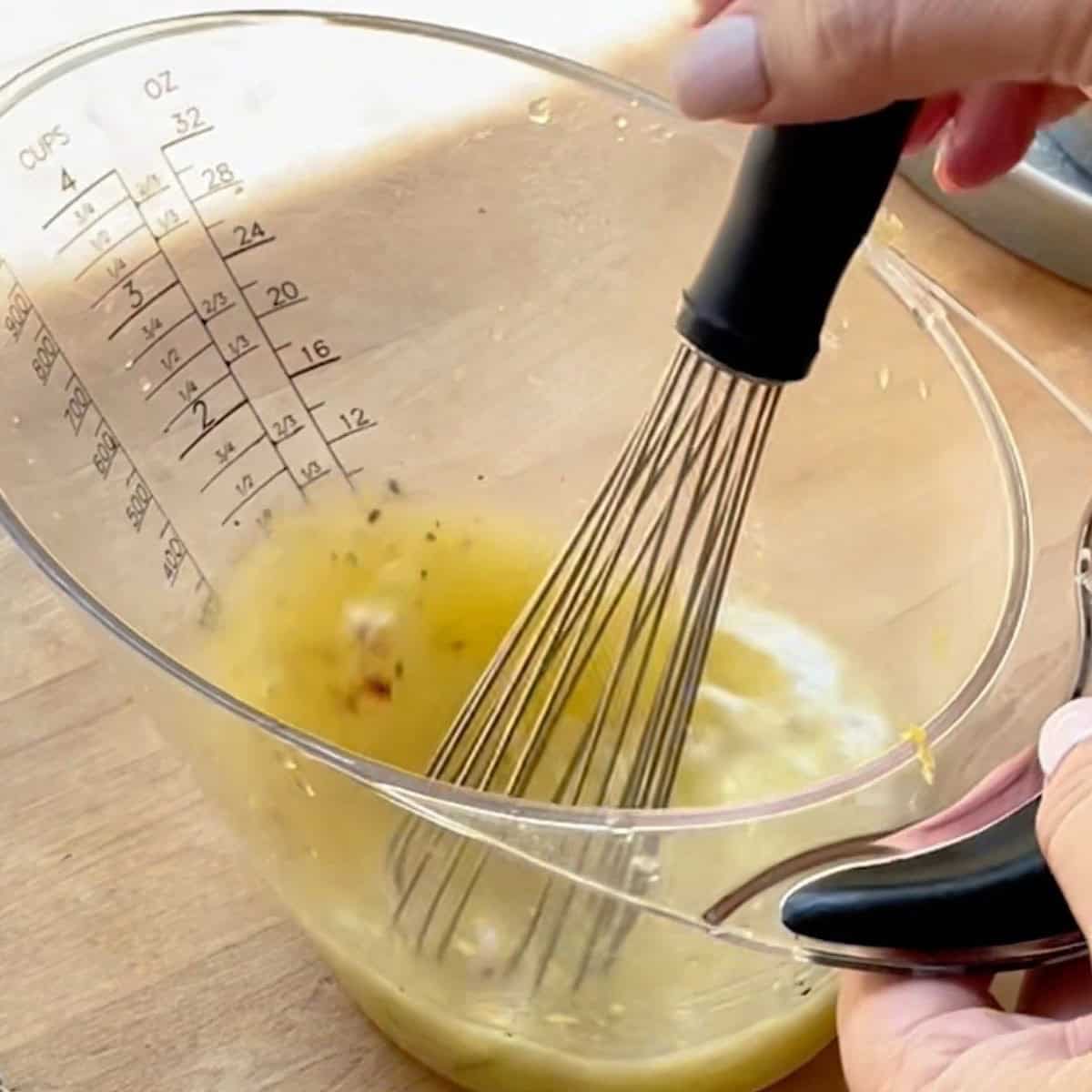 Whisking the garlic butter sauce in a measuring cup.