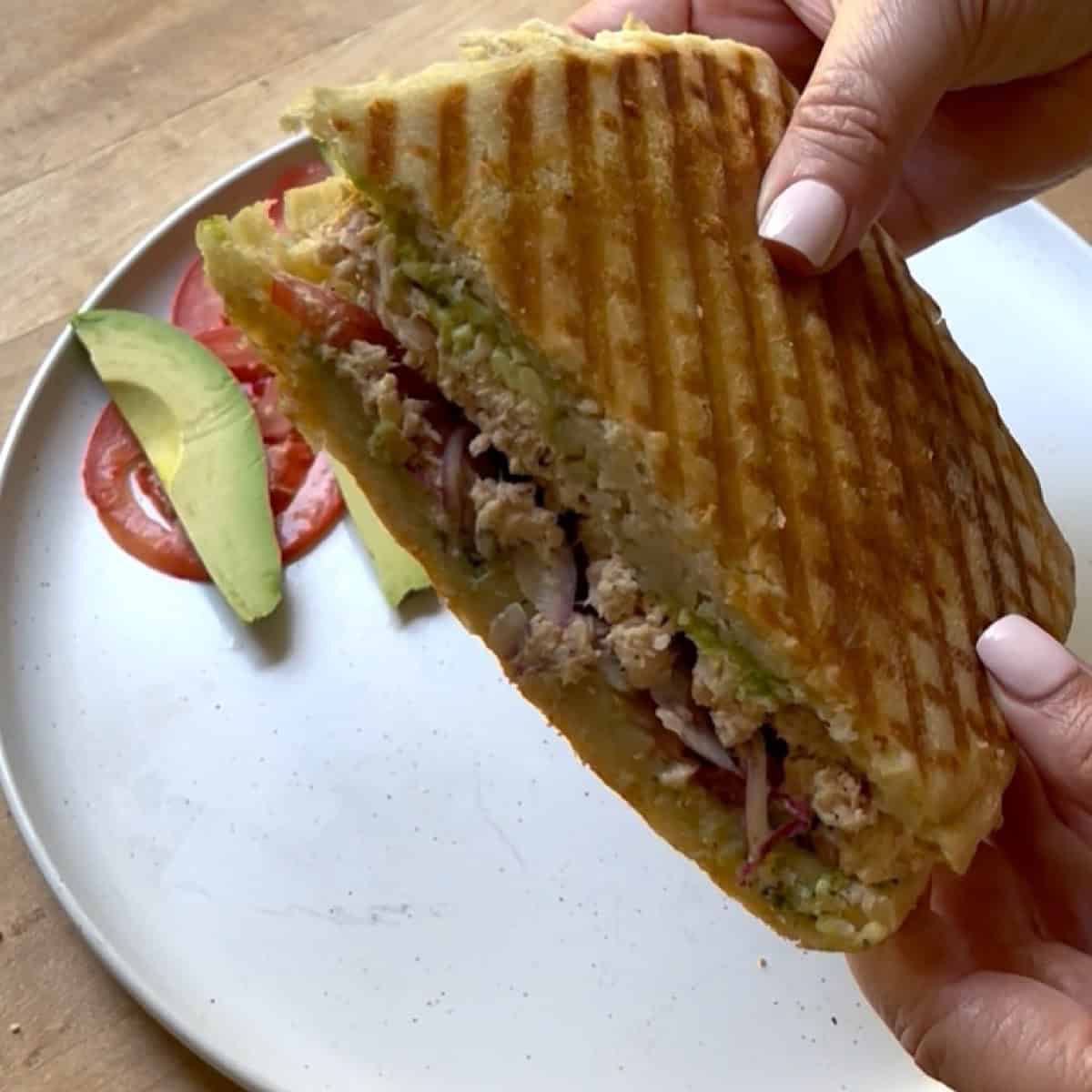Holding halved tunacado sandwich with inside showing.