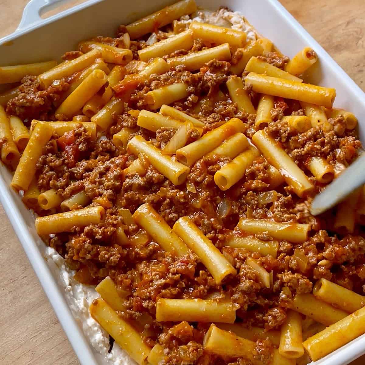 Ziti layered with cheese in the middle of ground beef and pasta.