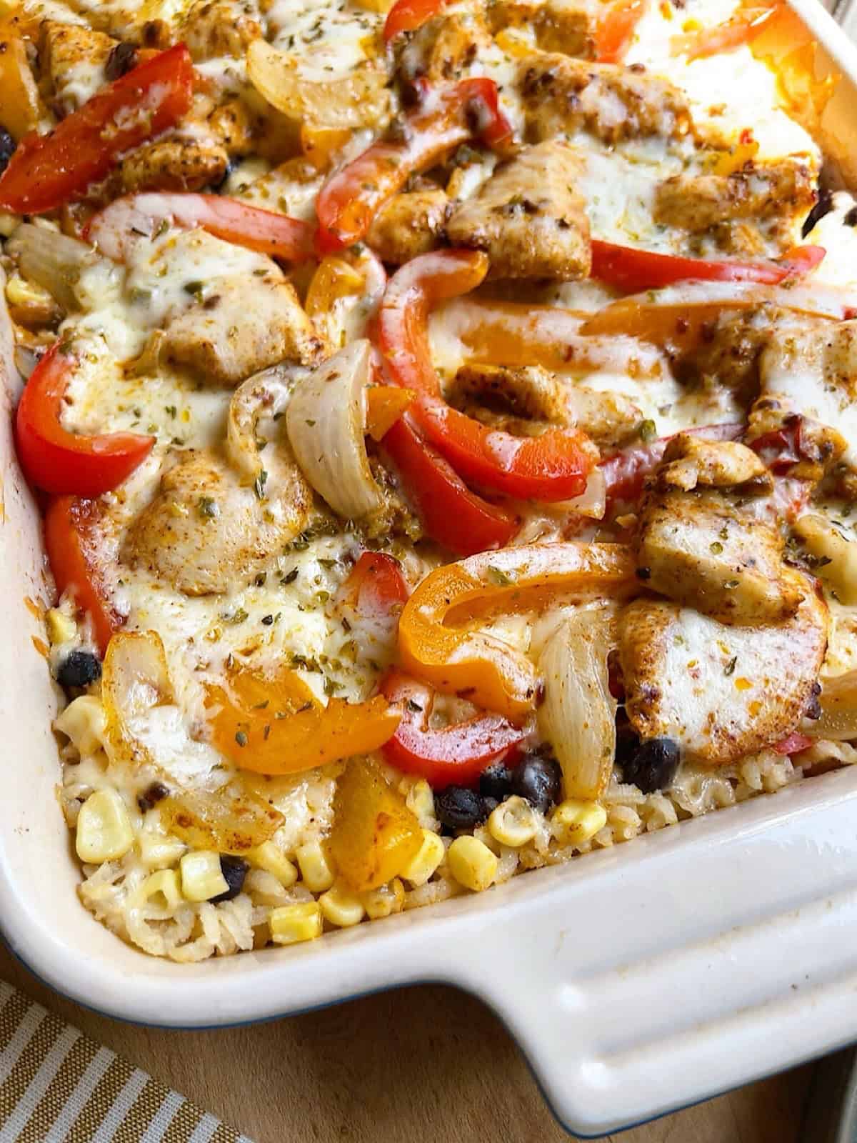 Cheesy chicken fajita bake with oregano sprinkled over top in a casserole dish.