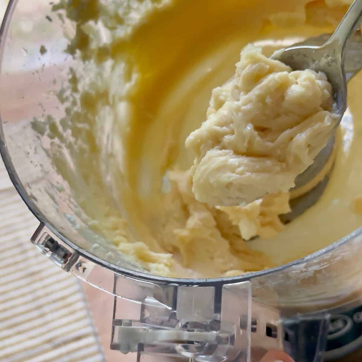 Honey butter mixed in a food processor with a spoon holding a scoop.