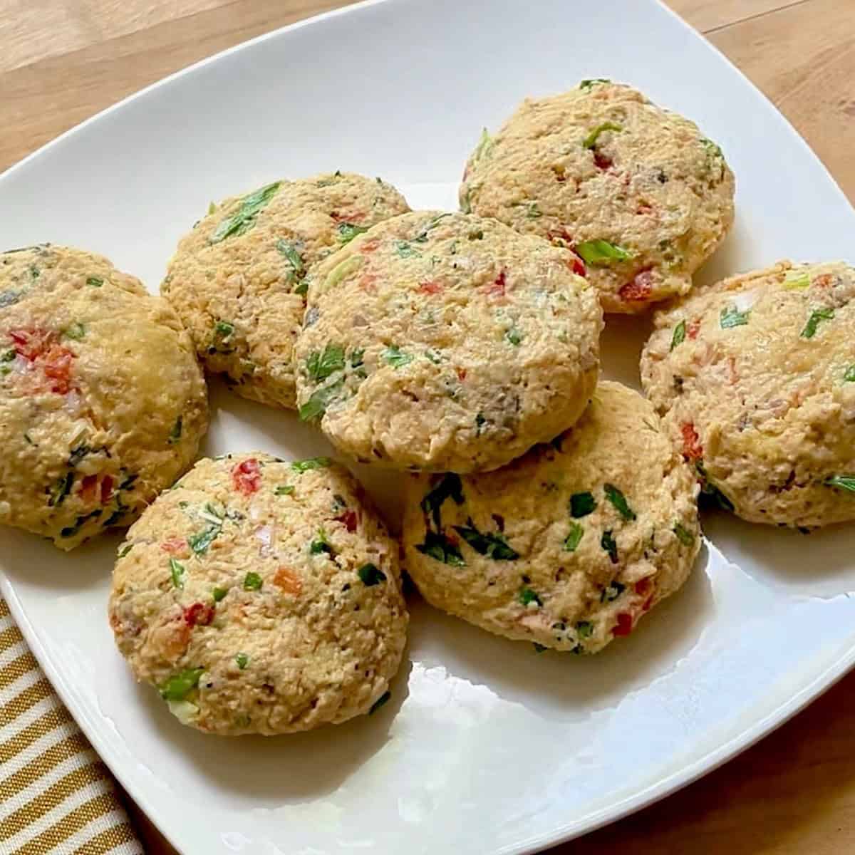 Seven salmon patties shaped on a plate.