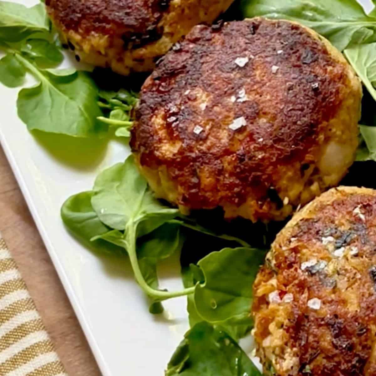 Cooked salmon patties on a bed of watercress greens.