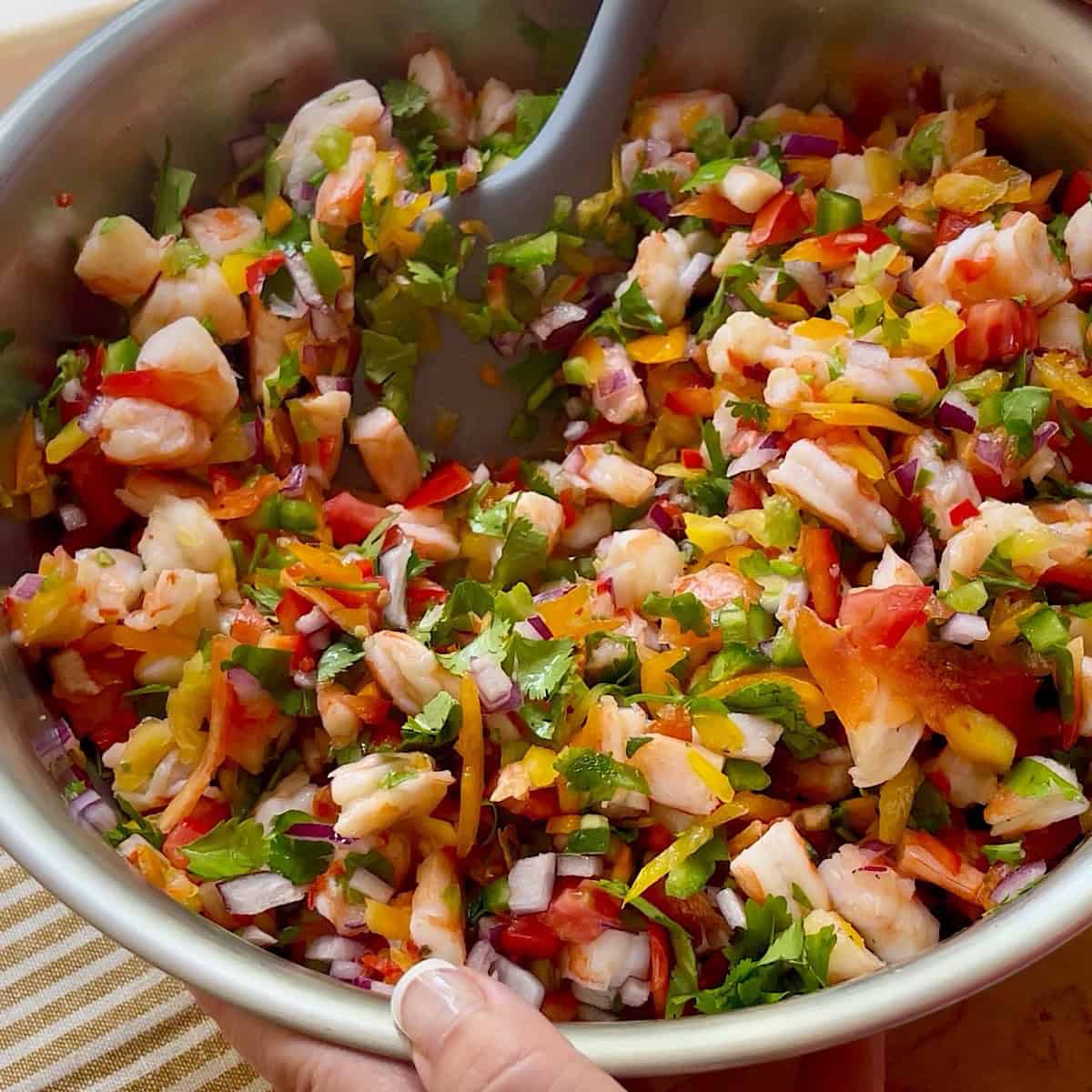 Combining ceviche ingredients in a large mixing bowl.