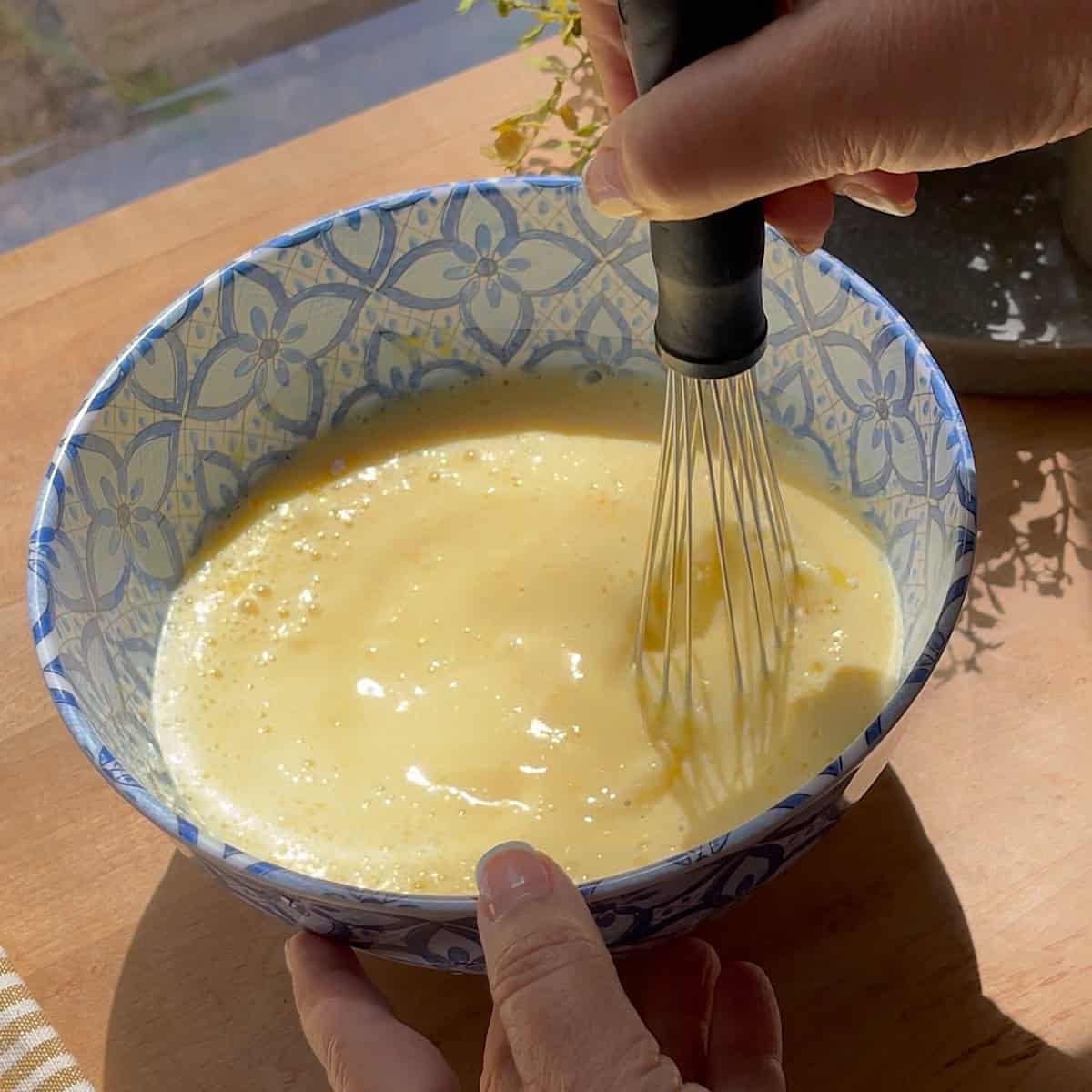 Pudding mix being whisked in a bowl with milk.