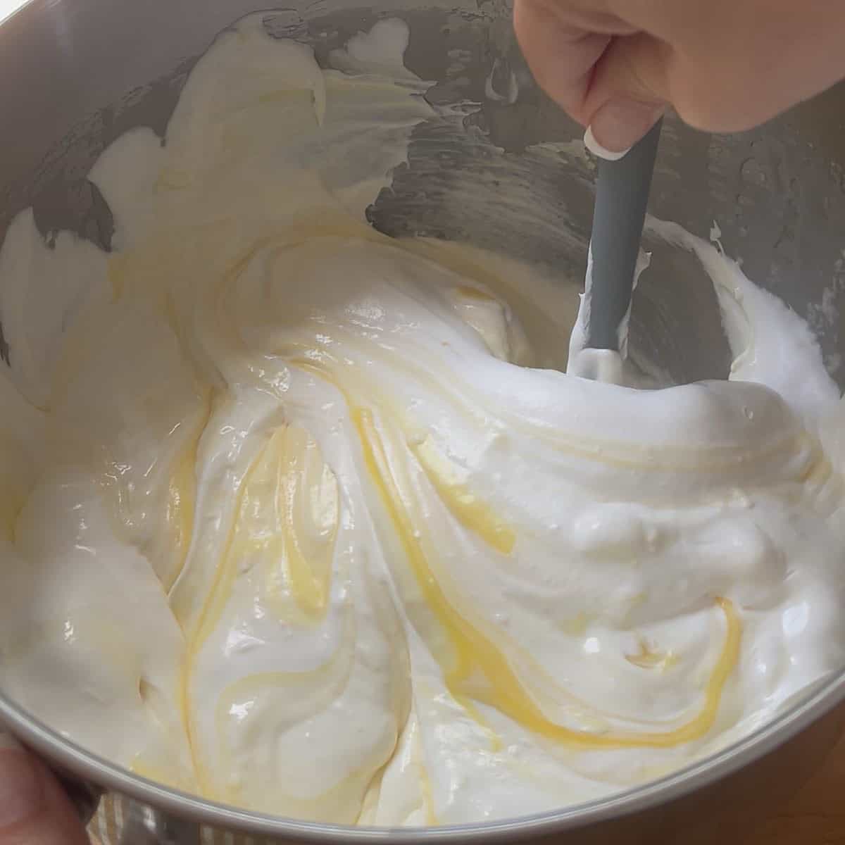 Folding cream cheese mixture with Cool Whip and pudding in a bowl.