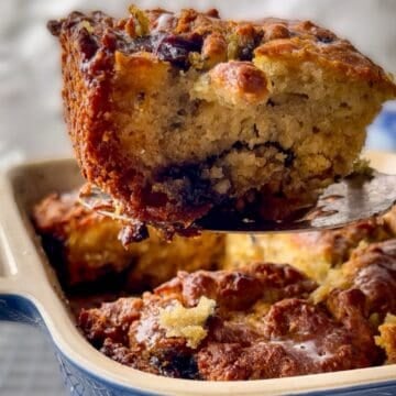 A swim butter biscuit held over the baking dish with a spatula.