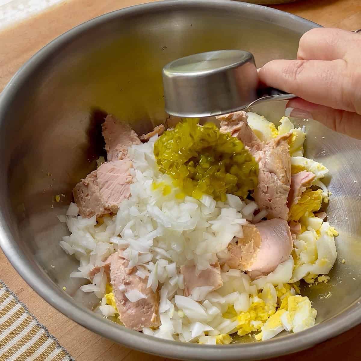 Adding relish to remaining tuna egg salad ingredients.