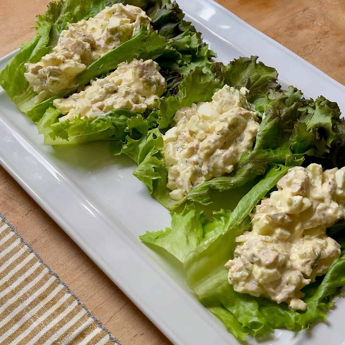 A platter of tuna egg salad resting on large pieces of red lettuce leaves.