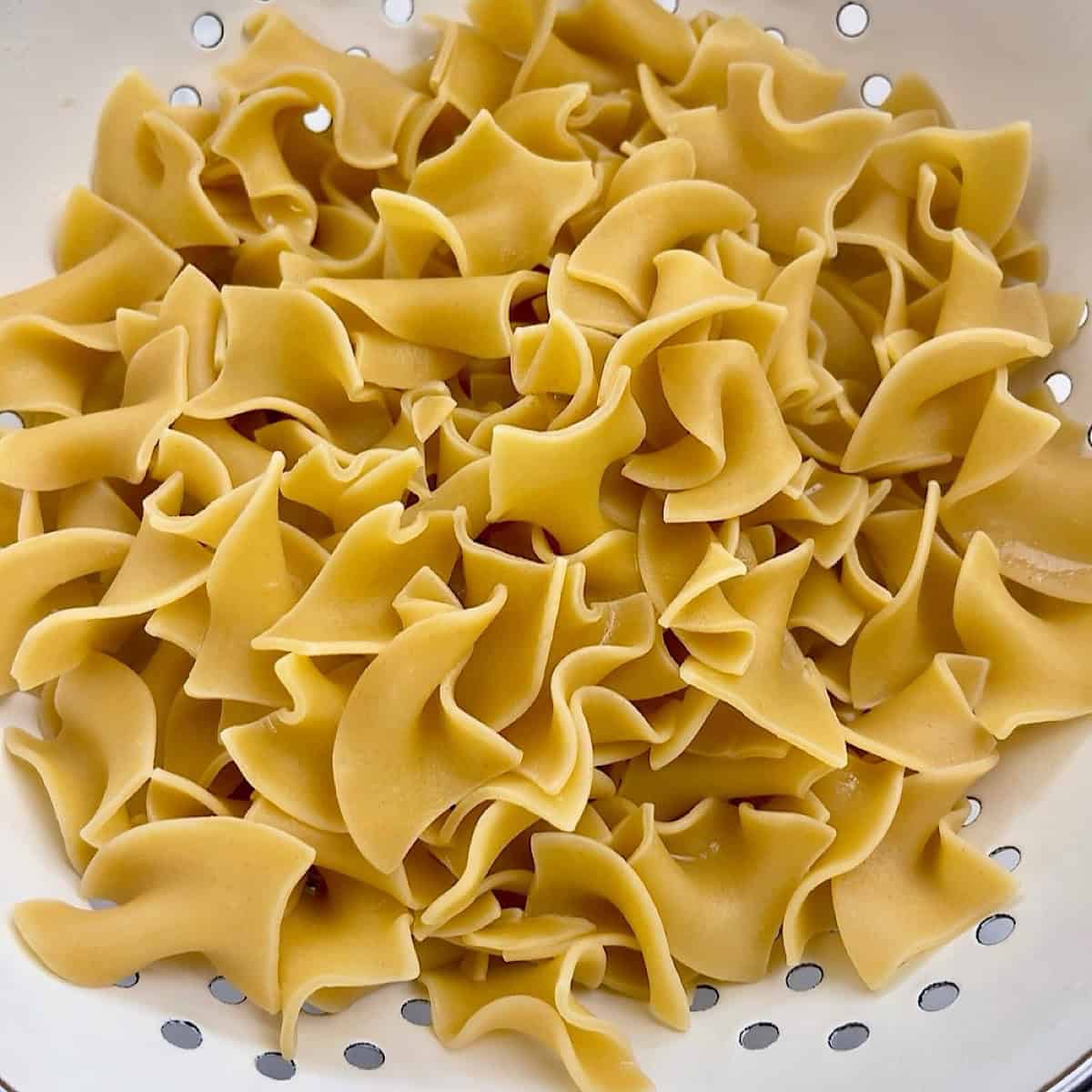Egg noodles draining in a colander.