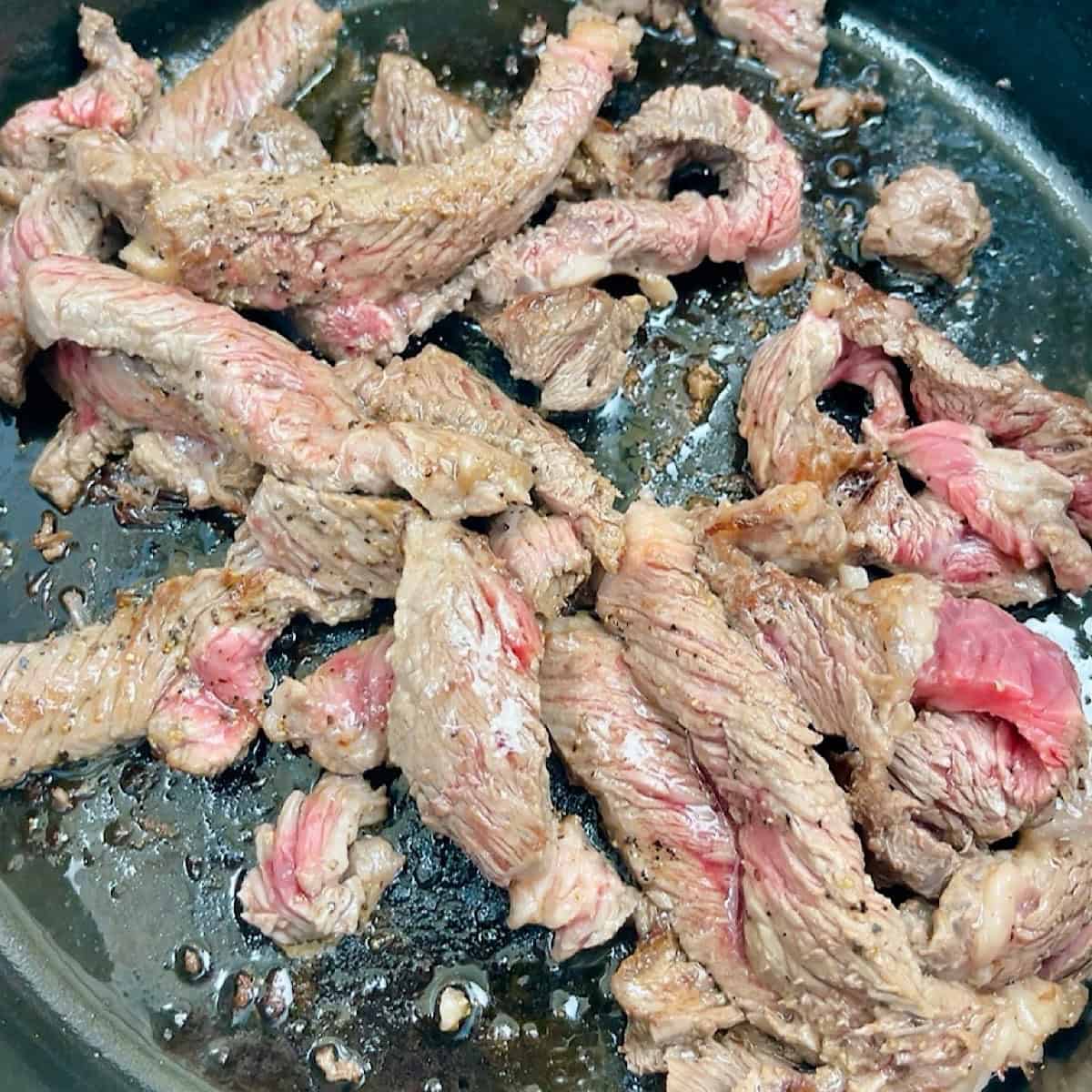 Ribeye steak strips searing in dutch oven.