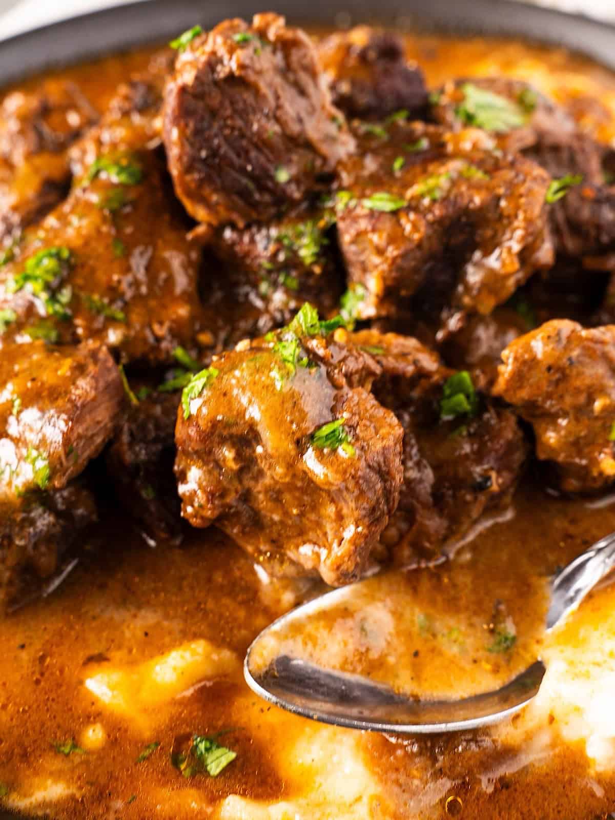 Beef tips with mashed potatoes in a bowl with spoon.