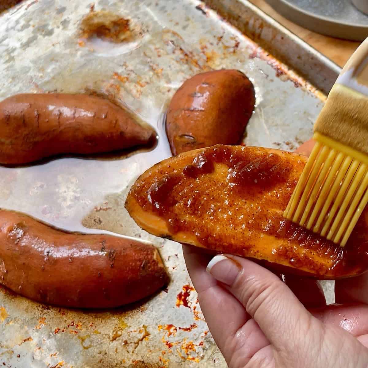 Applying the stickly glaze onto a sweet potato.