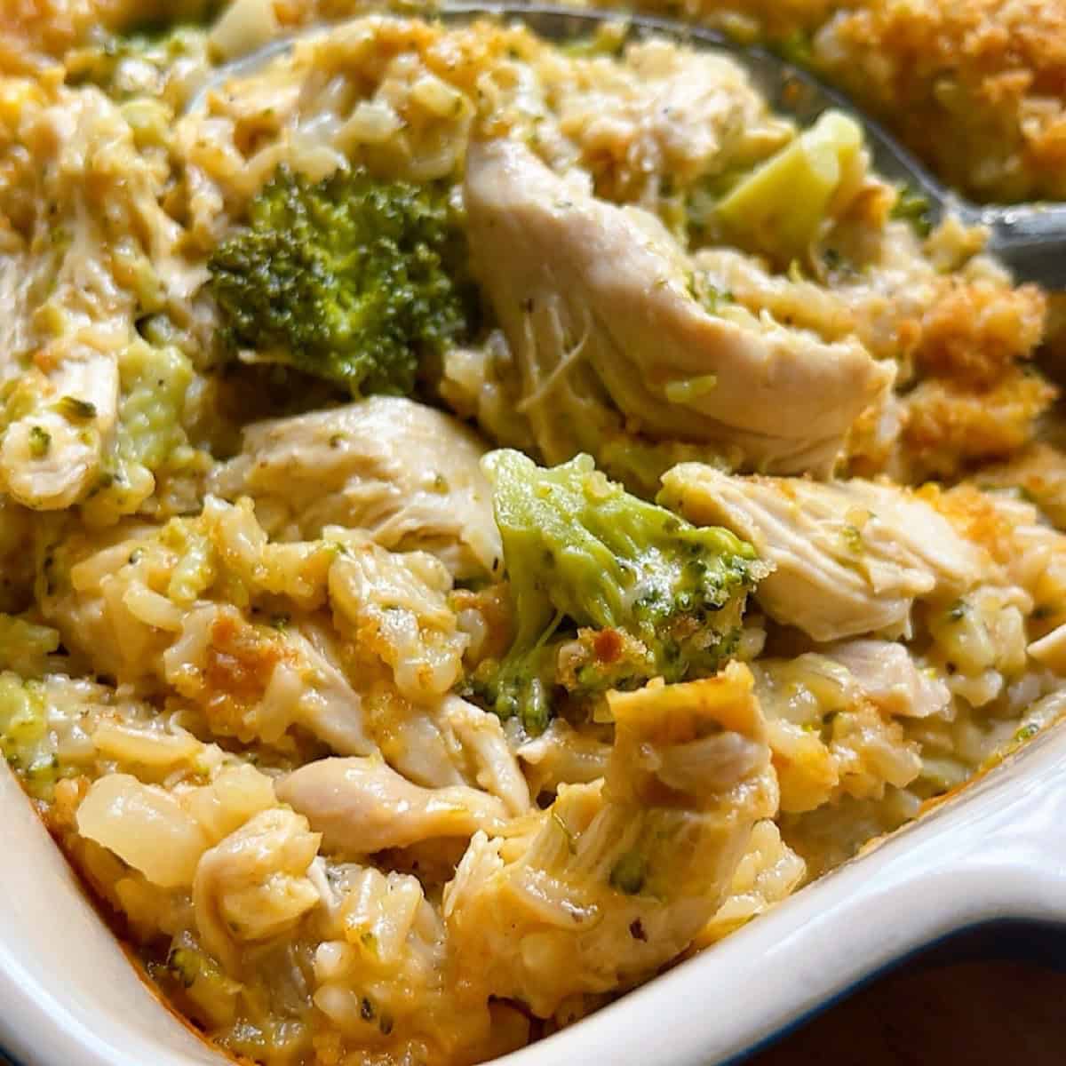 A large serving spoon in the chicken broccoli rice bake without soup to show the inside of the casserole.