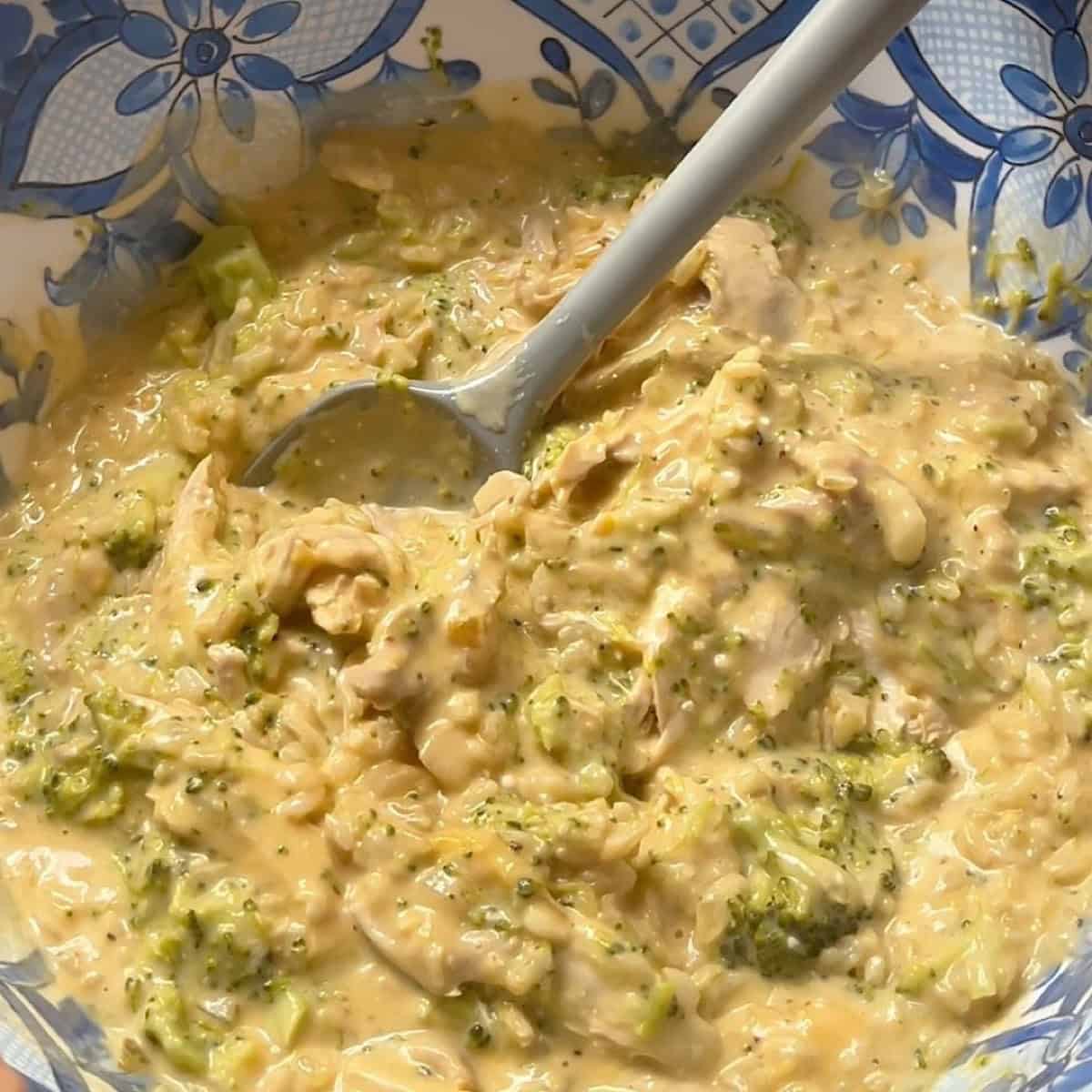 Combining the cheese sauce with other ingredients in a mixing bowl.