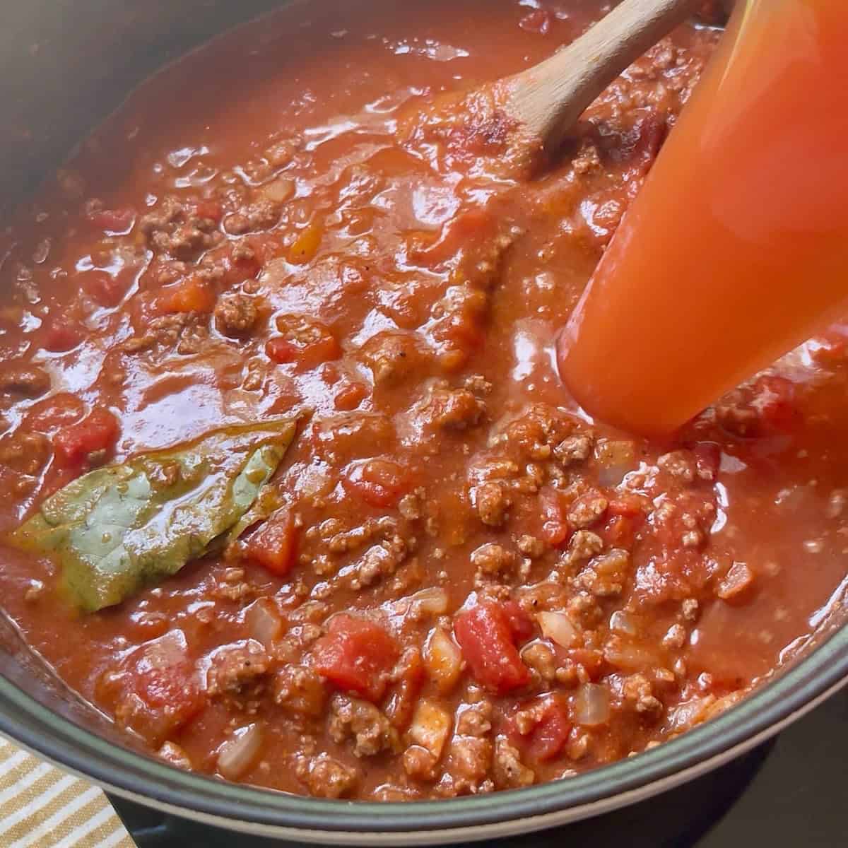 Adding water to the chili while it simmers.