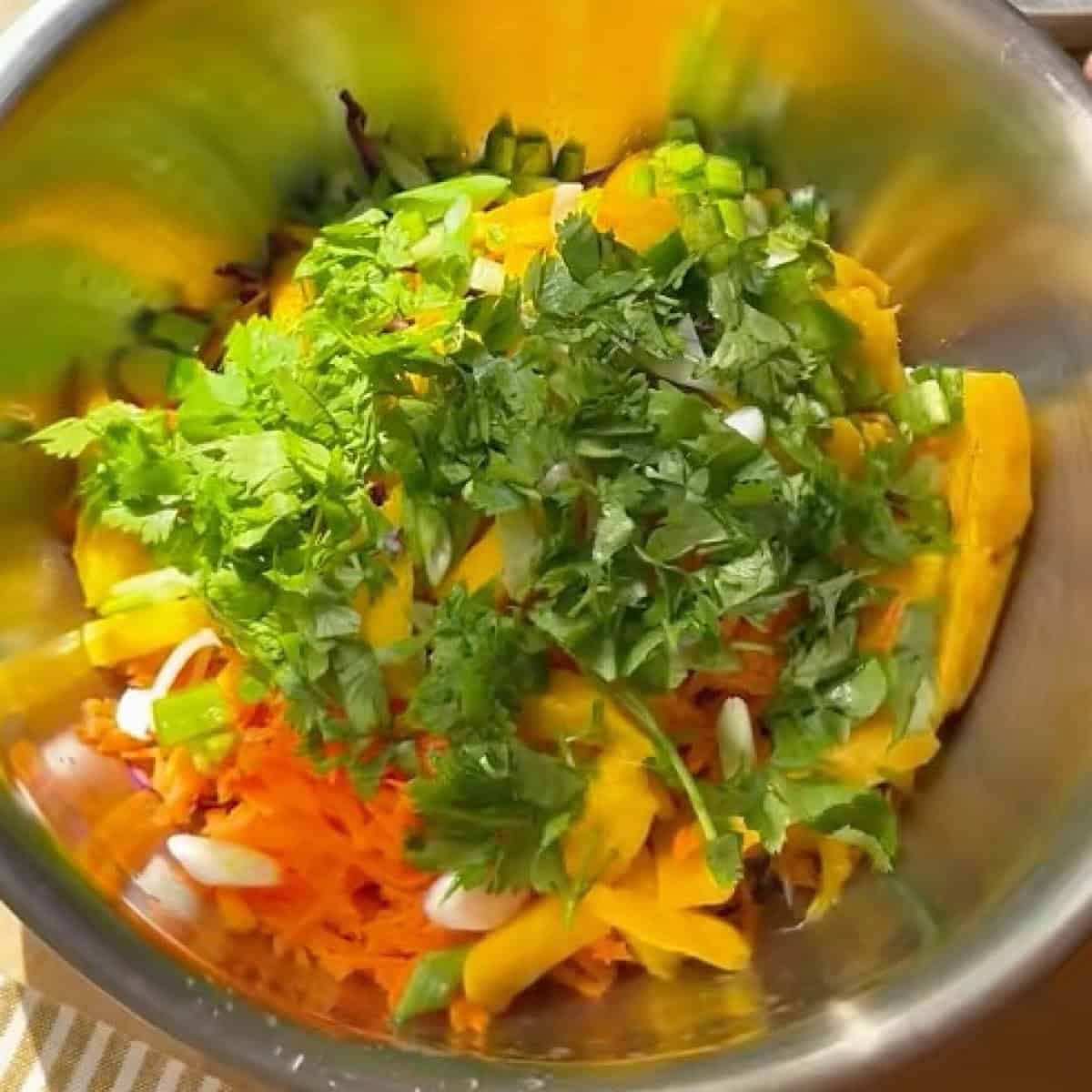 Prepped slaw ingredients in the same bowl with honey lime dressing.