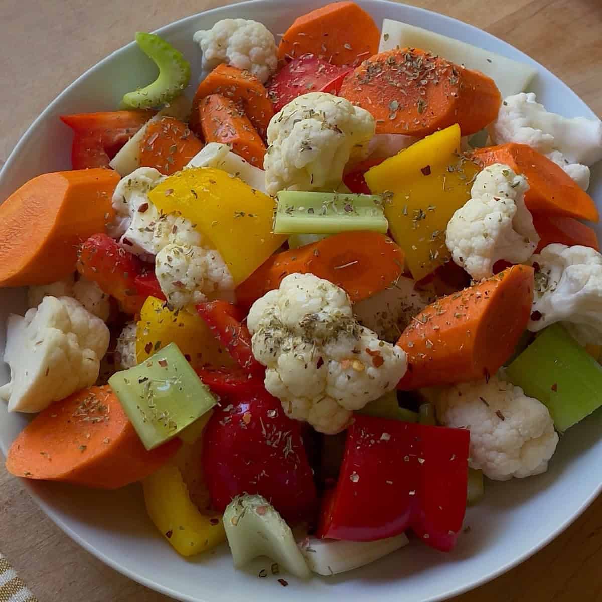 Giardiniera in a serving bowl garnished with oregano and drizzled with olive oil.