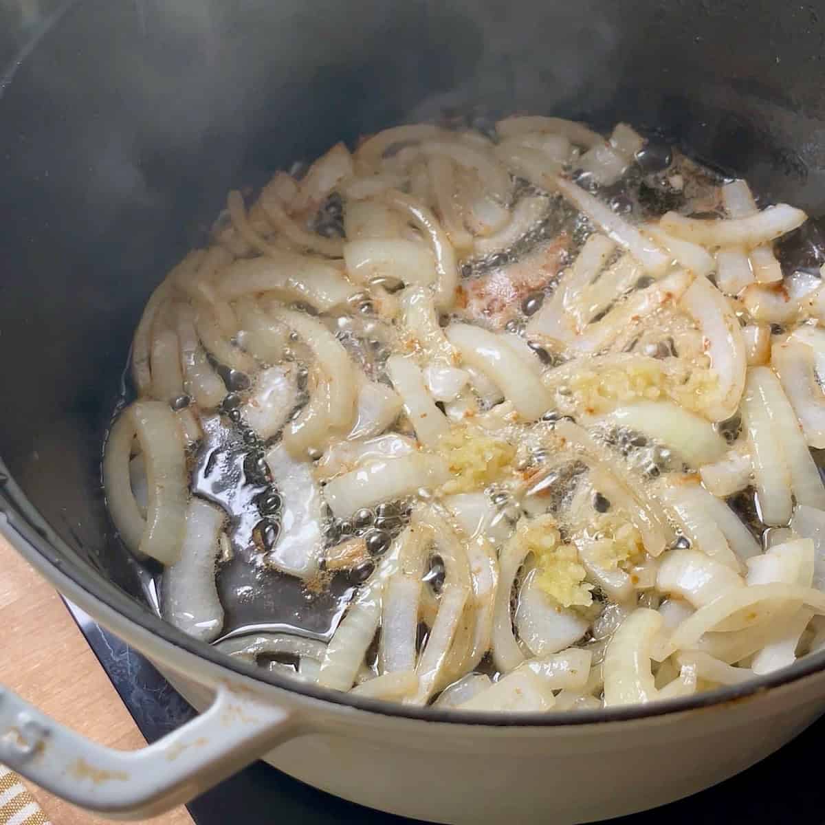 Onion sauteeing with garlic in a dutch oven.
